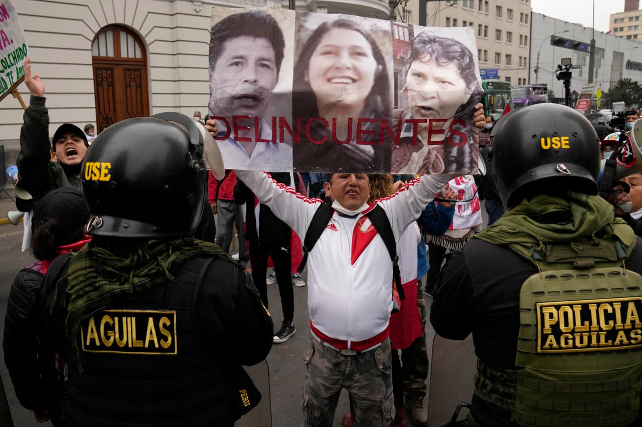 Un opositor de Pedro Castillo levanta una pancarta con fotos de su cuñada Yenifer Paredes y su esposa, Lilia Paredes, el 28 de agosto de 2022 en Lima.