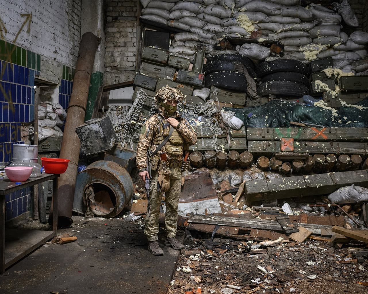 Un soldado ucraniano frente a una barrera levantada con sacos de arena y cajas de munición vieja en un edificio una zona industrial de Donbas.