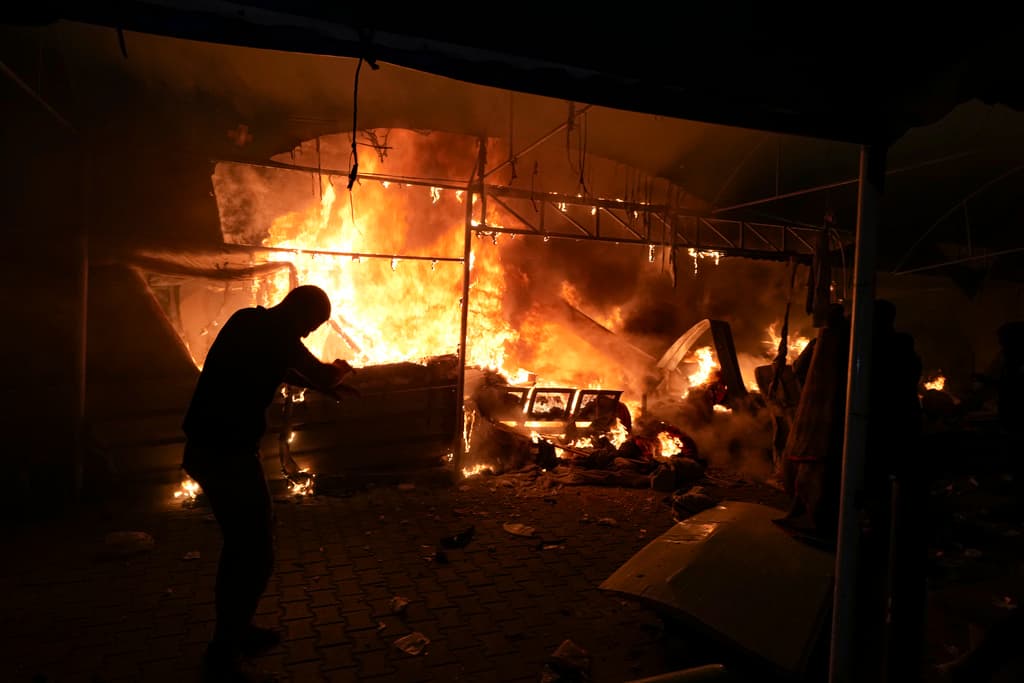 Palestinos reaccionan a un incendio después de que un ataque israelí golpeara una zona de tiendas en el patio del Hospital 'Mártires de Al Aqsa' en Deir al Balah, en la Franja de Gaza, la madrugada del lunes 14 de octubre de 2024.