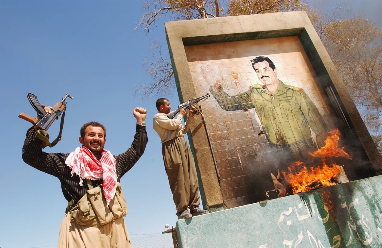 <b>EEUU exige una zona autónoma kurda en Irak.</b> Aunque EEUU no apoyó directamente a los kurdos contra Hussein, mantuvo una zona de exclusión de vuelos sobre el norte de Irak que ayudó a asegurar cierto grado de autonomía kurda. 
<a href="https://www.univision.com/noticias/ataques/operacion-libertad-iraqui-la-invasion-en-busca-de-unas-armas-de-destruccion-masiva-que-saddam-hussein-no-tenia-fotos">Tras la caída de Hussein en 2003</a>, Washington se aseguró de que la nueva Constitución de Irak consagrara esa zona autónoma. En la fotografía, combatientes iraquíes kurdos celebran la toma de la ciudad norteña de Kirkuk en abril de 2003 y destruyen un mural de Saddam Hussein.
