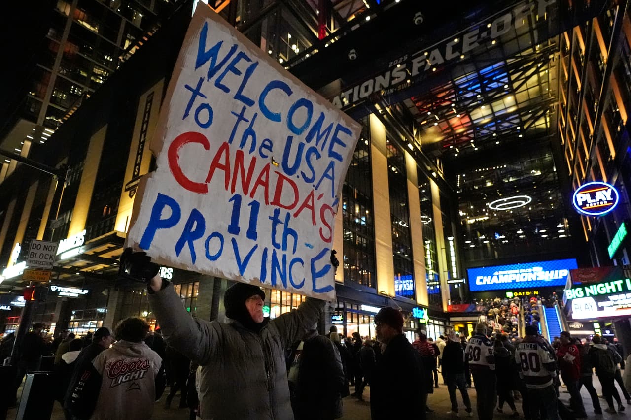 "Bienvenidos a EEUU, la decima primera provincia de Canadá", dice el cartel de este aficionado, mientras el público ingresa al Boston Garden, antes del partido de hockey entre Estados Unidos y Canadá.