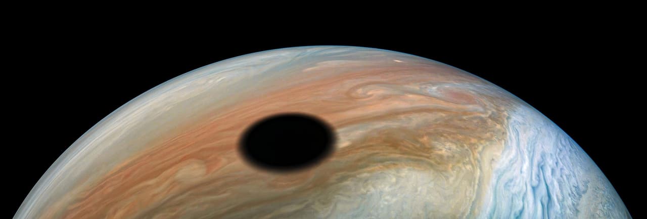 La sombra de la luna Io sobre la superficie de Júpiter, tal como ocurre con los eclipses lunares en nuestro planeta.
<br>
<br>Júpiter es diferente a los otros ocho planetas de nuestro sistema solar. Los científicos creen que el núcleo del planeta podría ser rocoso, de resto el gigante está formado solo de elementos líquidos y gaseosos. La atmósfera de Júpiter tiene una capa de hidrógeno metálico líquido.
<br>