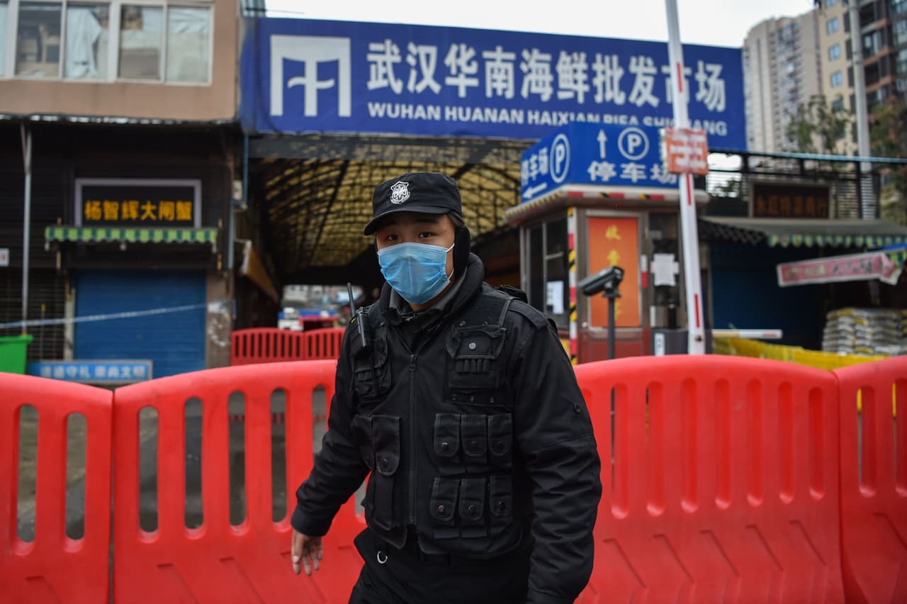 <b>El mercado donde todo empezó (1 de enero).</b> Las autoridades sanitarias de China clausuraron el mercado mayorista de mariscos de Huanan al sospechar que los animales salvajes vendidos allí podían ser la fuente del nuevo coronavirus. Esta fotografía del 24 de enero muestra a un policía custodiando este local. Los primeros enfermos de neumonía en esa ciudad se reportaron entre el 12 y el 29 de diciembre y China informó su preocupación la OMS el 31 de ese mes.