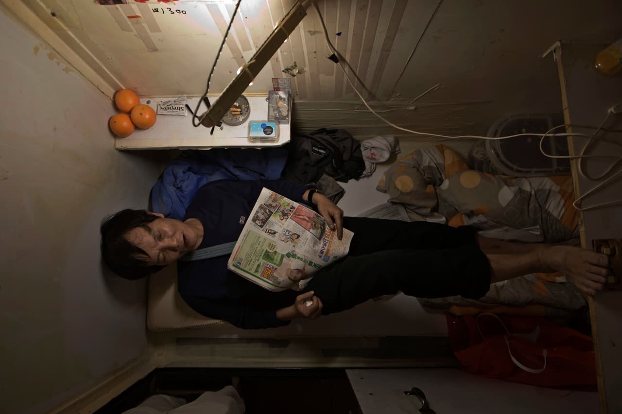 Yeung, residente de una ‘casa ataud’, lee y descansa en el diminuto espacio.