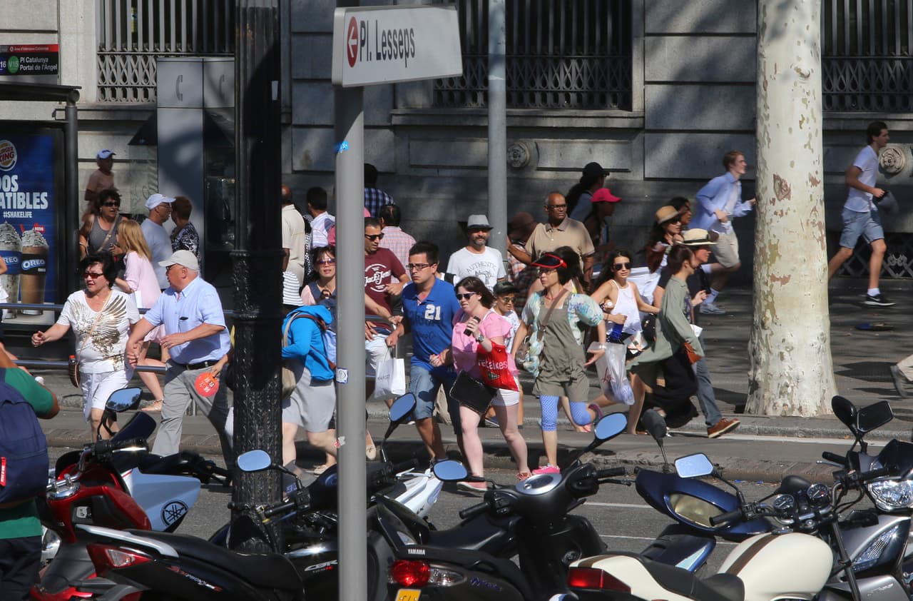 En la imagen se ve a la gente que huye de la Rambla, después de que una furgoneta blanca subiera a la acera en el histórico distrito. La policía ha pedido que la gente no se acerque a la zona.