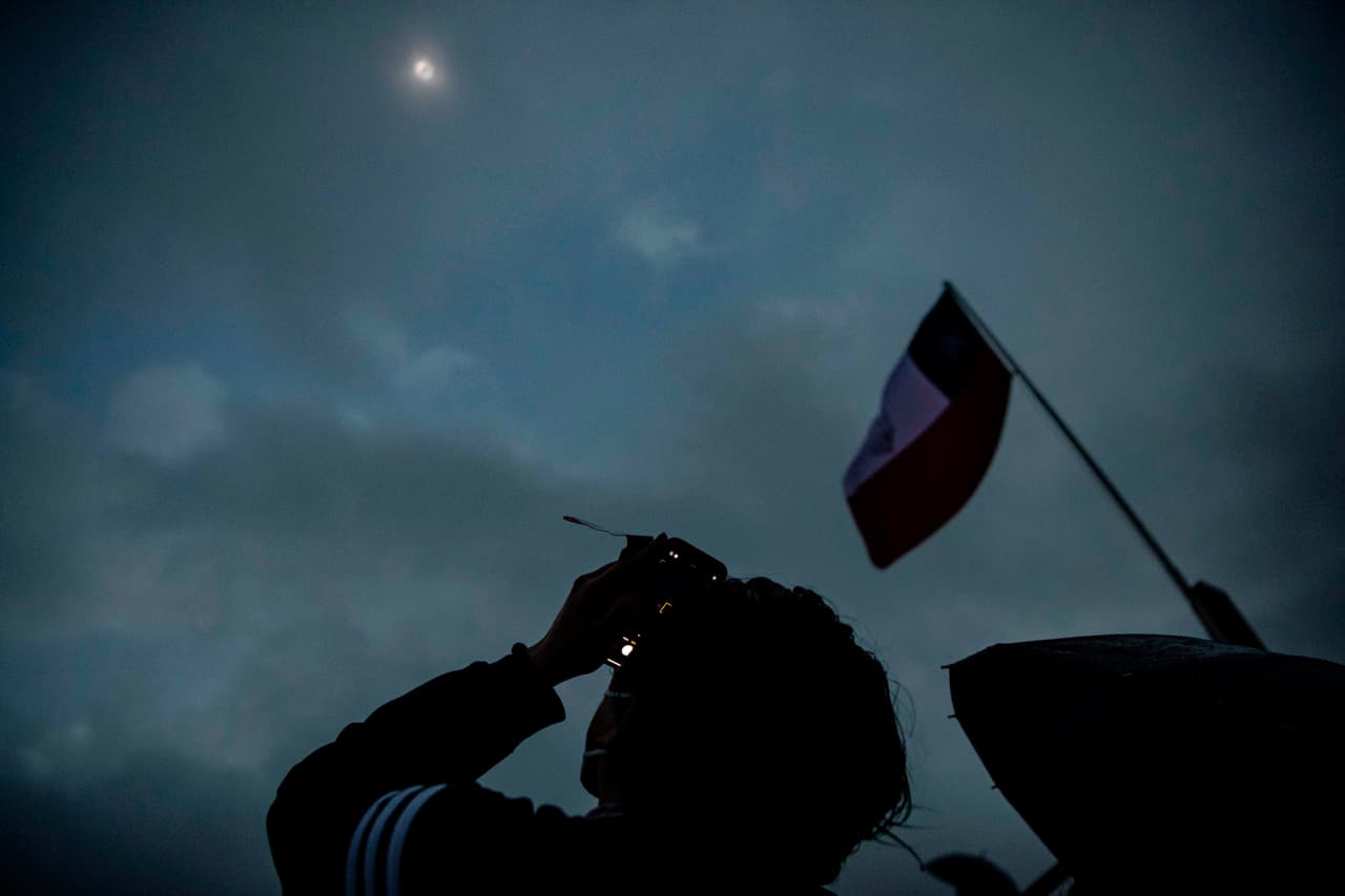 Un hombre toma fotografías del eclipse total de sol en Pucón, Chile, en medio de las nubes y lluvia que entorpeció la visibilidad del fenómeno. 
<br>
<br>Fue descrito por la NASA como una "coincidencia celestial", oscureciendo a Chile y Argentina en pleno día.