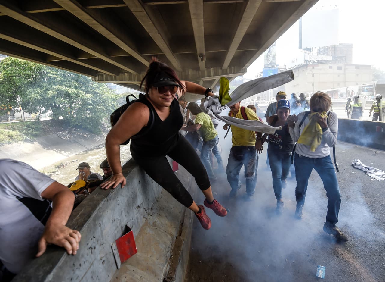 Los opositores al régimen de Nicolás Maduro huyen del gas lacrimógeno lanzado por la policía y de las aguas sucias del río Guaire.