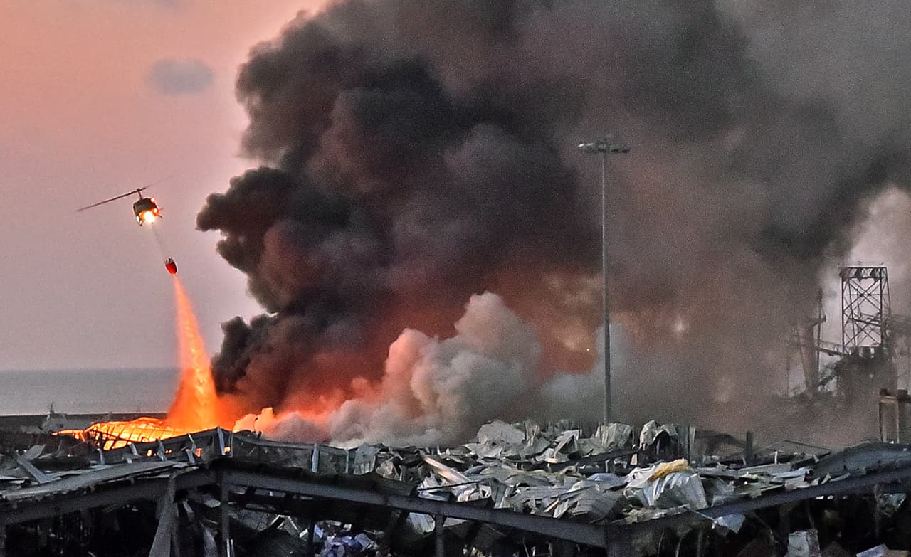 Un helicóptero de los bomberos intenta sofocar el fuego en el puerto de Beirut.