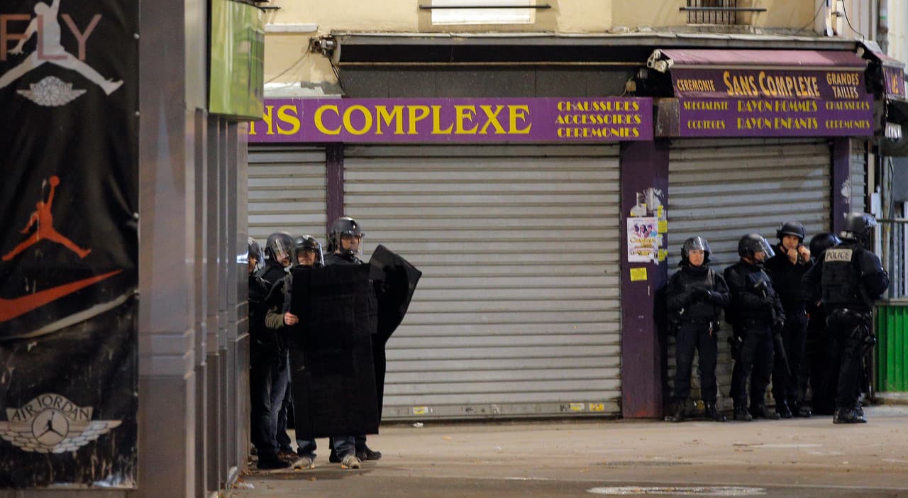 Fuerzas policiales se resguardan en la esquina de una calle del suburbio de Saint Denis