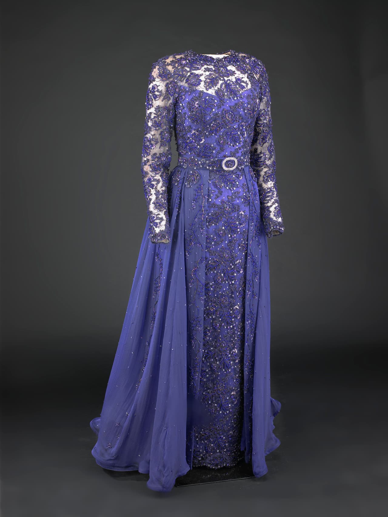 El vestido púrpura de encaje y brocado y con unas iridisencias azules fue efectivamente diseñado por 
<b>Sarah Phillips</b> pero fue hecho por la casa Barabara Matera, una afamada productora de vestidos de teatro de Nueva York. Sus zapatos fueron de Bruno Magli y su clutch Judith Leiber.
