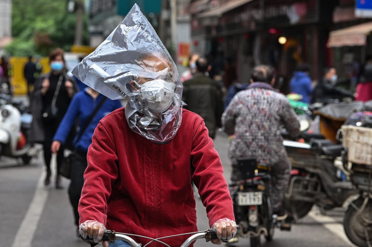 “Un hombre protegiéndose contra el virus con una bolsa plástica en una calle de Wuhan, el 14 de abril. Al regresar a Wuhan Retamal notó que a los periodistas “en las calles los policías nos paraban y nos decían que regresáramos a nuestro hotel”. 
<br>