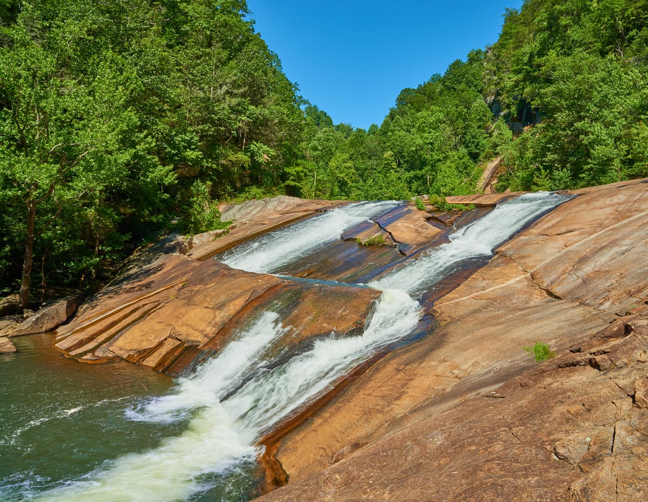 <b>Georgia.</b>
<br>
<br>Las Cascadas Bridal Veil, en el 
<a href="https://gastateparks.org/TallulahGorge" target="_blank">Parque Estatal Tallulah Gorge de Georgia</a> son un enorme atractivo en verano. Pozos de agua y toboganes de piedra naturales hacen que sea atractivo para familias que escapan del calor. El parque advierte que cuando llega demasiada gente y el estacionamiento se llena al máximo, el personal del parque puede limitar temporalmente el acceso.
