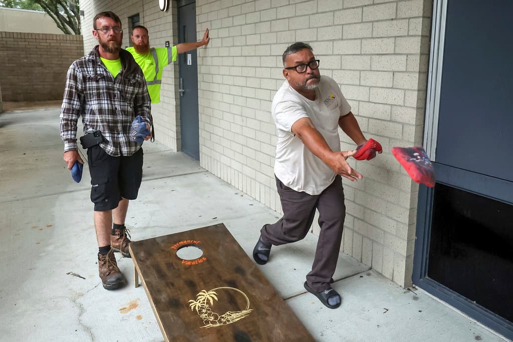 <b>Sacan el estrés: </b>David Siver, a la izquierda, y Edwin Rodríguez, trabajadores de servicios públicos del condado de Pasco, juegan al cornhole mientras se preparaban para el huracán Milton en el refugio de la escuela secundaria River Ridge, el miércoles 9 de octubre de 2024, en New Port Richey, Florida.