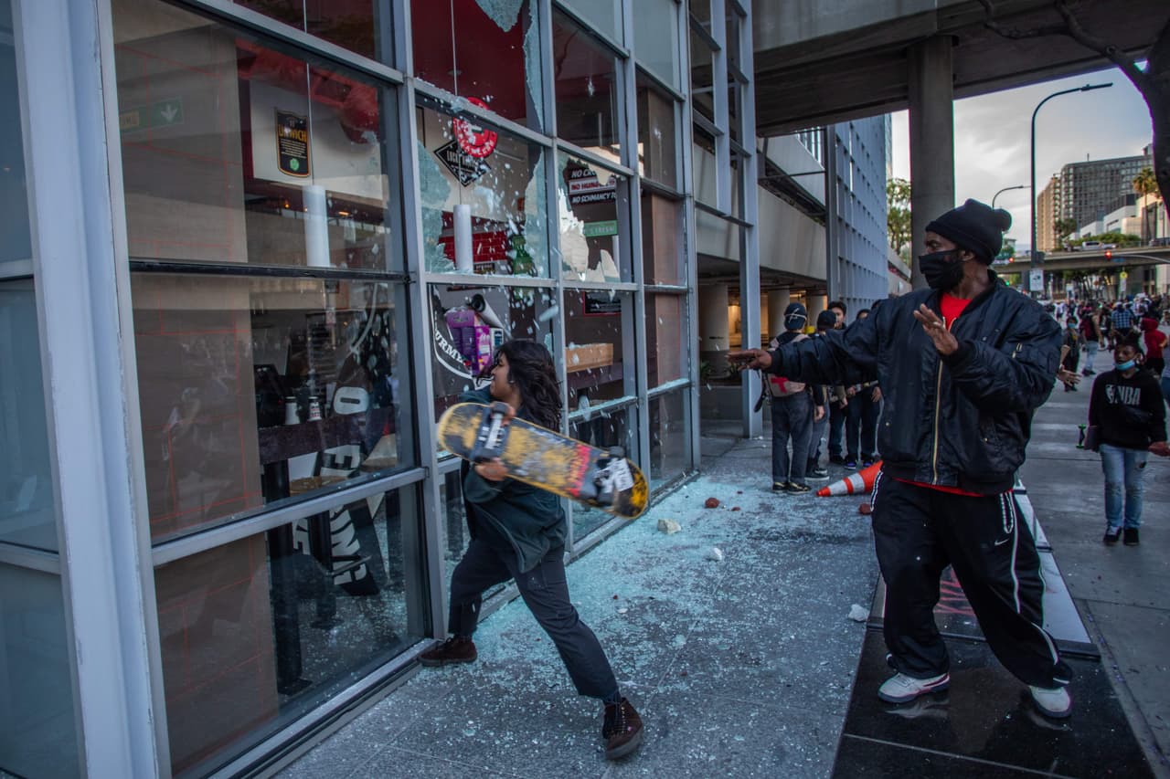 Del otro lado del país las protestas por la muerte de Floyd también se tornaron violentas. En la fotografía un manifestante vandaliza un restaurante del centro de Los Ángeles. 30 de mayo.