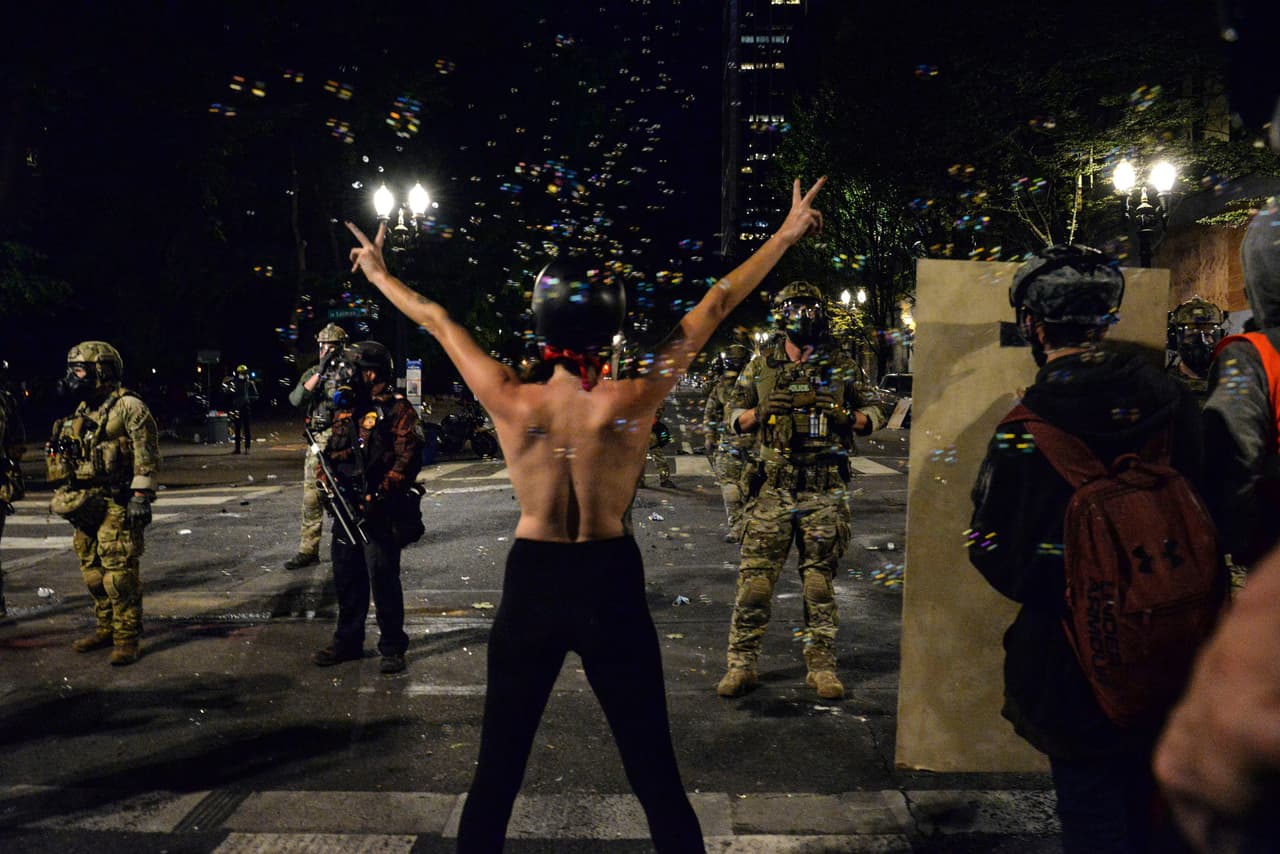<b>Una protesta creativa contra las fuerzas federales. </b>Una mujer sin camisa reta a los agentes federales enviados por Trump a Portland, Oregon, el 26 de julio. En esta ciudad hubo intensas protestas durante meses.