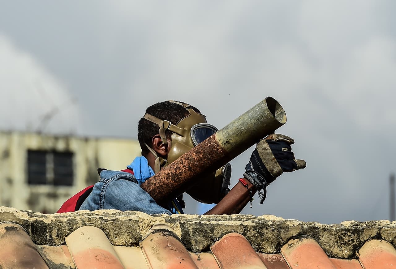 Armado con un lanzador de fuego artificiales, un manifestante opositor se prepara para atacar a la fuerza pública que intenta disolver una manifestación en Caracas.
