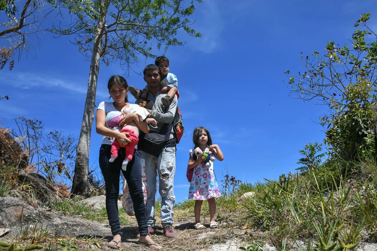 Según el informe de UNICEF el éxodo venezolano ha provocado que los países de tránsito y acogida estén sufriendo una sobrecarga que dificulta la prestación de servicios esenciales como protección, atención sanitaria y educación. En la foto un oficial de policía venezolano y su familia cuando caminaron en busca de refugio en Brasil, en la frontera de Pacaraima, estado Roraima, en febrero de 2019.