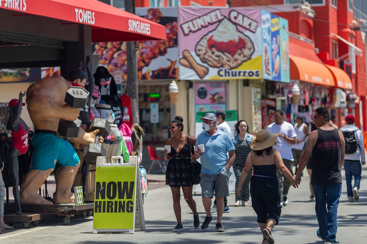 Una tienda anuncia una vacante de trabajo mientras que los bañistas se dirigen a Venice Beach el Día de los Caídos. La creciente ola de calor también se suma a la tentación de reunirse en las playas.
