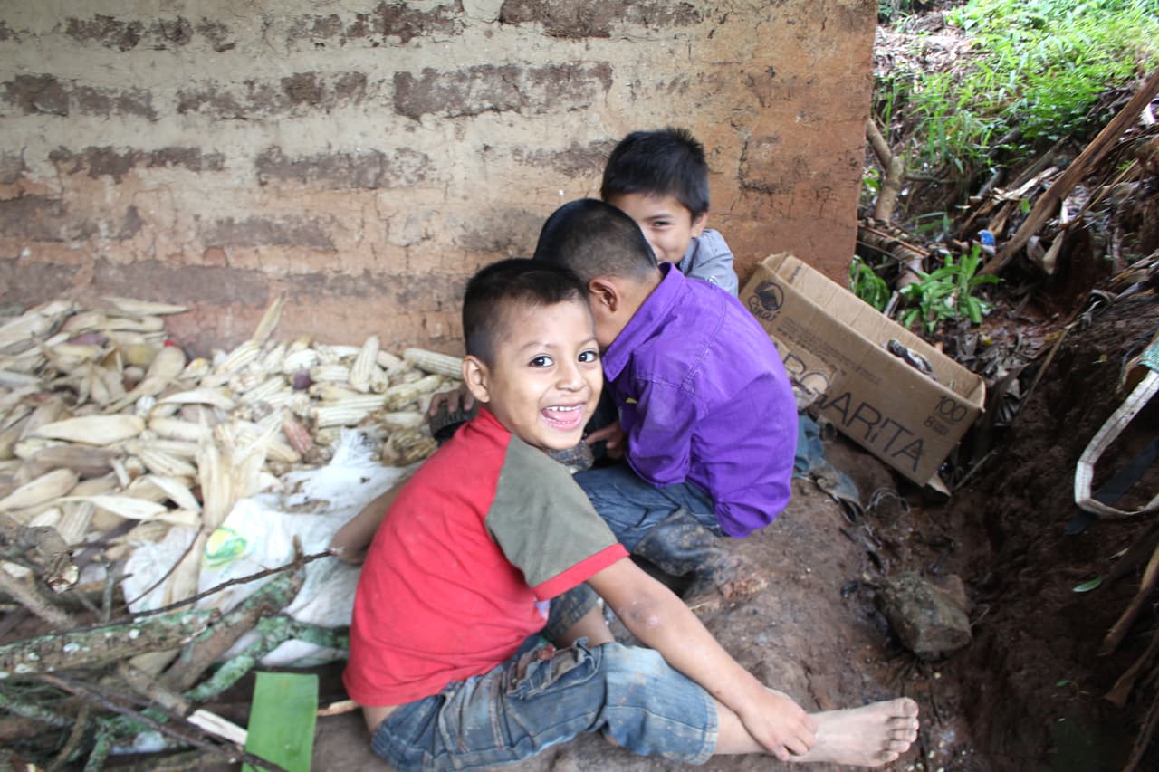 The farmer's sons Sergio (in red) and Dayro (in purple) play outside the house with their friend.