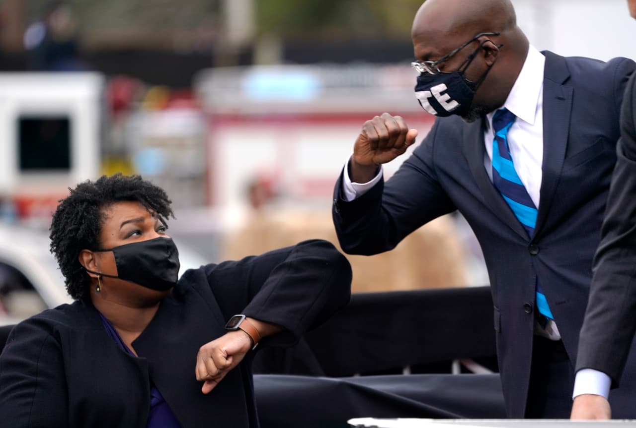 El candidato demócrata al Senado de Estados Unidos, Raphael Warnock choca los codos con Stacey Abrams durante un mitin de campaña con el presidente electo Joe Biden en Atlanta, Georgia. La visita de Biden en Georgia se produce a menos de un mes antes de la segunda vuelta de las elecciones el próximo 5 de enero.
