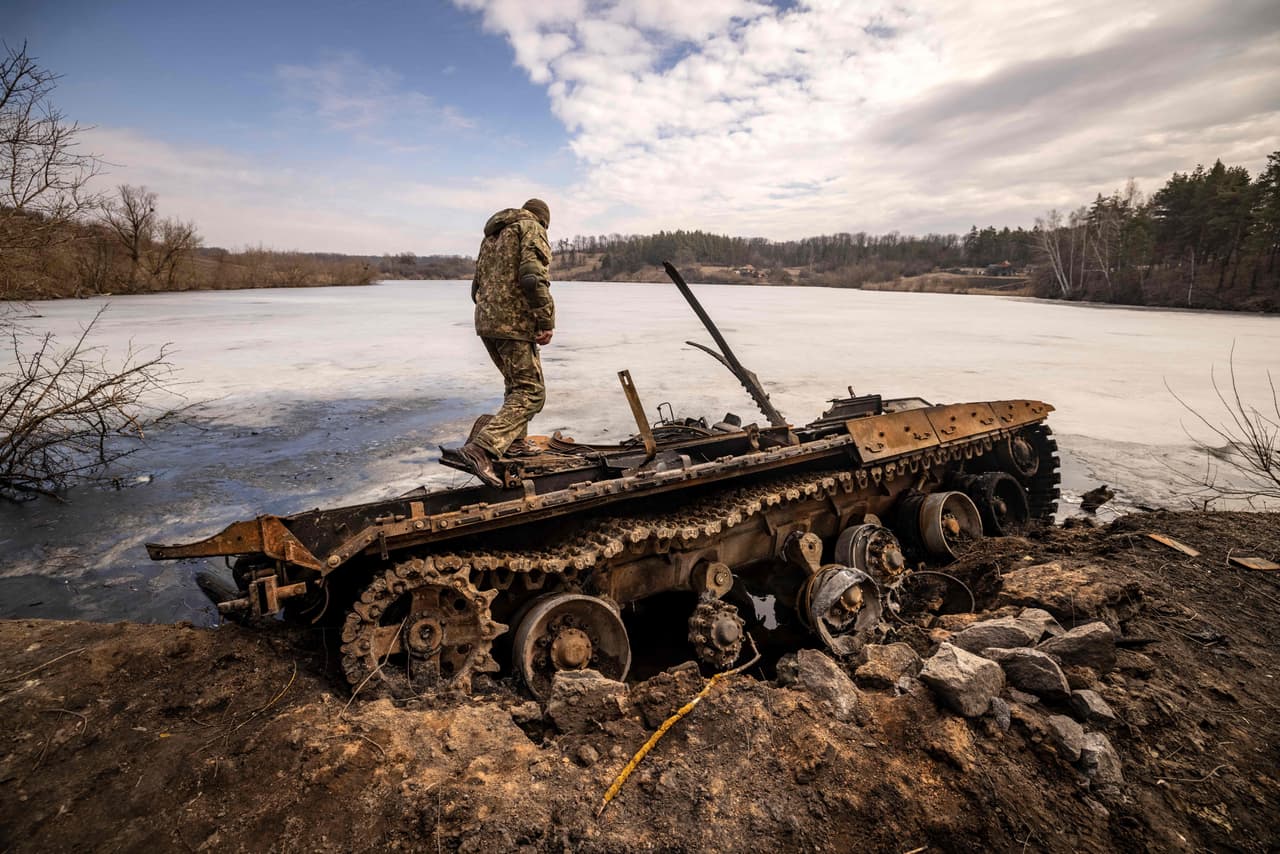 Un militar ucraniano se encuentra cerca de un vehículo de guerra ruso. Los tanques rusos yacen quemados, retorcidos, abandonados al igual que los cuerpos de muchos soldados en los bosques. 
<br>
<br>