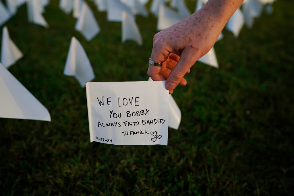 En la imagen, Zoe Nassimoff, originario de Argentina, sostiene una bandera blanca en la que escribió un mensaje a su abuelo que vivía en Florida y quien murió de covid-19.