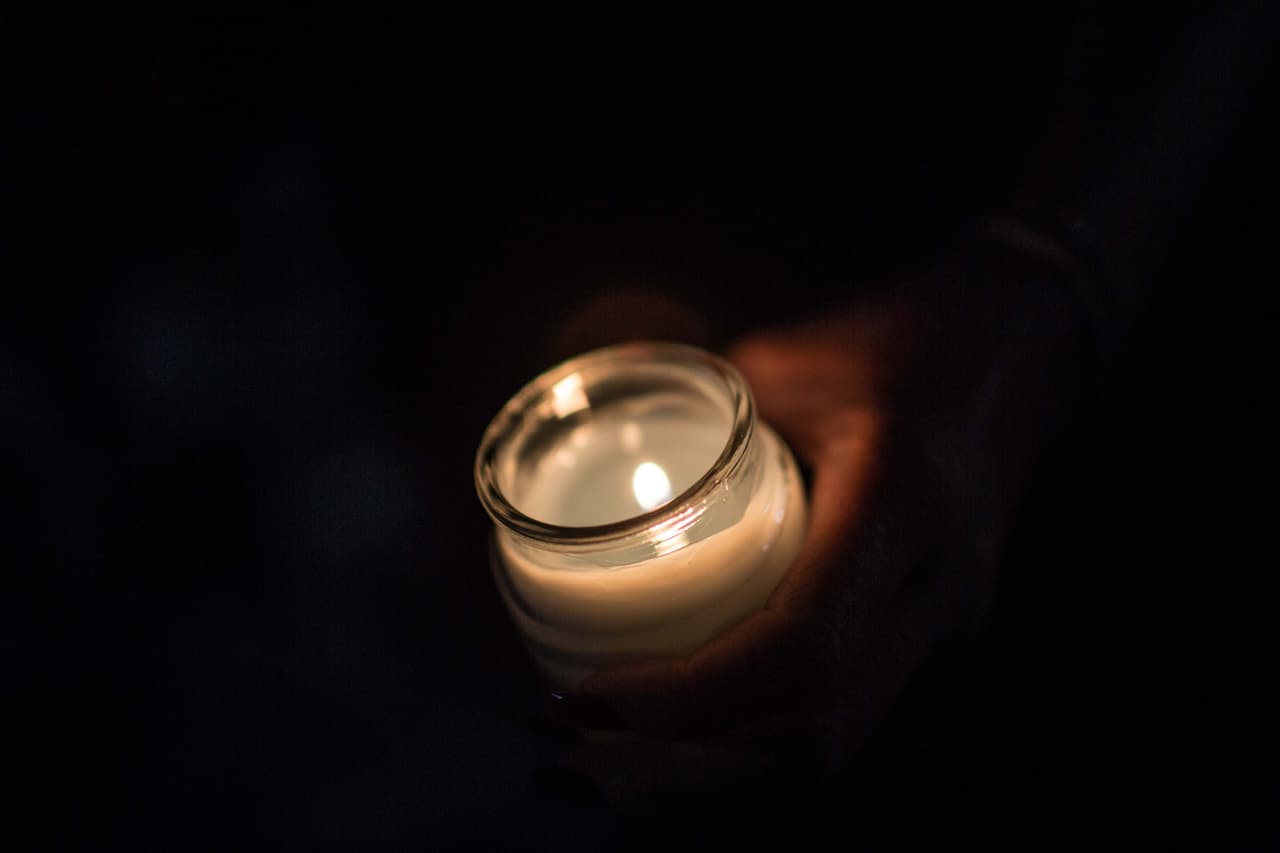 Una estudiante de la escuela sujeta una vela durante la vigilia. "¿Se ven los nombres?", pregunta. Escribió en su mano en tinta roja los nombres de sus mejores amigos. Dice estar agradecida de que están vivos.