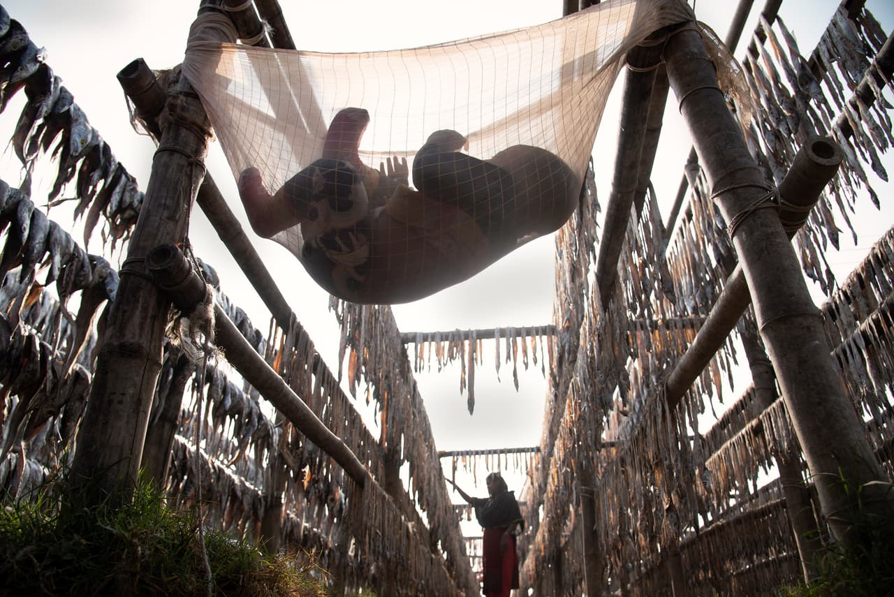 <b>‘Madre trabajadora’</b>
<br>
<br>Esta fotografía finalista muestra a una mujer trabajando en un área donde se secan pescados, mientras su hijo la espera. 
<br>
<br>“Aunque todo el lugar está llenó de aire tóxico de pescado podrido y seco, la mujer debe continuar buscando el sustento de su familia”, explicó el concurso. “Además, debe cuidar a su hijo mientras cumple sus obligaciones laborales”.
<br>