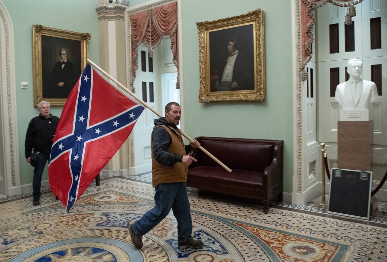 <b>La bandera Confederada</b>
<br>
<br>El principal símbolo de los Estados Confederados de América, un intento de división territorial que fracasó después de llevar al país a una cruenta guerra civil, fue visto dentro y fuera del Capitolio el 6 de enero de 2021.
<br>
<br>Como explicó Joe Biden en su discurso para 
<a href="https://www.univision.com/noticias/politica/asalto-al-capitolio-en-vivo-ultimas-noticias-del-aniversario-ataque-capitolio-de-eeuu-6-de-enero-de-2021"><u>conmemorar el primer aniversario </u></a>del ataque de los partidarios de Donald Trump a la institución, está bandera jamás había entrado en la sede de alguno de los poderes públicos estadounidenses.
<br>
<br>
<a href="https://www.univision.com/noticias/politica/explosiones-asaltos-tiroteos-incendios-fotografias-historicas-furia-violencia-capitolio-estados-unidos-fotos"><u>Vea aquí las fotografías históricas de cuando la furia entró al Capitolio de Estados Unidos</u></a>