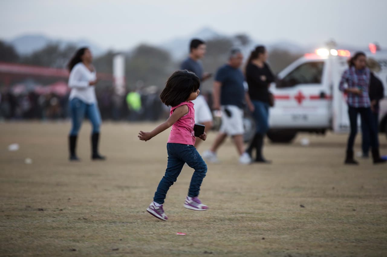 Una niña corre por la explanada del concierto con un celular inteligente en la mano. Dos de cada tres personas en México posee un teléfono inteligente, en un país donde el 46.2% vive en la pobreza. 
<i>Almudena Toral</i>