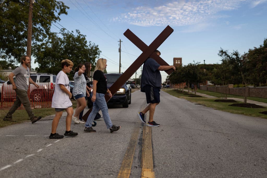 Cargando una cruz, símbolo de resurreción para los cristianos, llegó una de las 
<b>cientos de familias</b> que se congregaron en el 
<b>parque</b> 
<b>Jug Tavern</b> de la ciudad de 
<b>Winder, en Georgia</b>, en busca de consuelo tras el 
<b><a href="https://www.univision.com/local/atlanta-wuvg/madre-christian-angulo-asesinato-asesinado-apalachee-high-school" target="_blank">tiroteo mortal ocurrido en la Apalachee High School</a></b>, este 4 de septiembre.