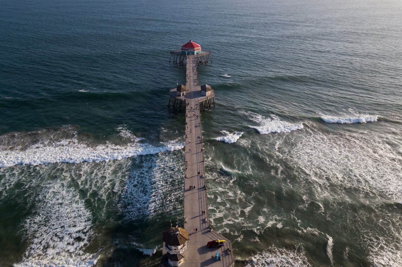 In this aerial image, people walk on the Huntington Beach pier before sunset on May 19, 2021 in Huntington Beach, California. - Orange County is now in the state's least-restrictive yellow tier of reopening. (Photo by Patrick T. FALLON / AFP) (Photo by PATRICK T. FALLON/AFP via Getty Images)