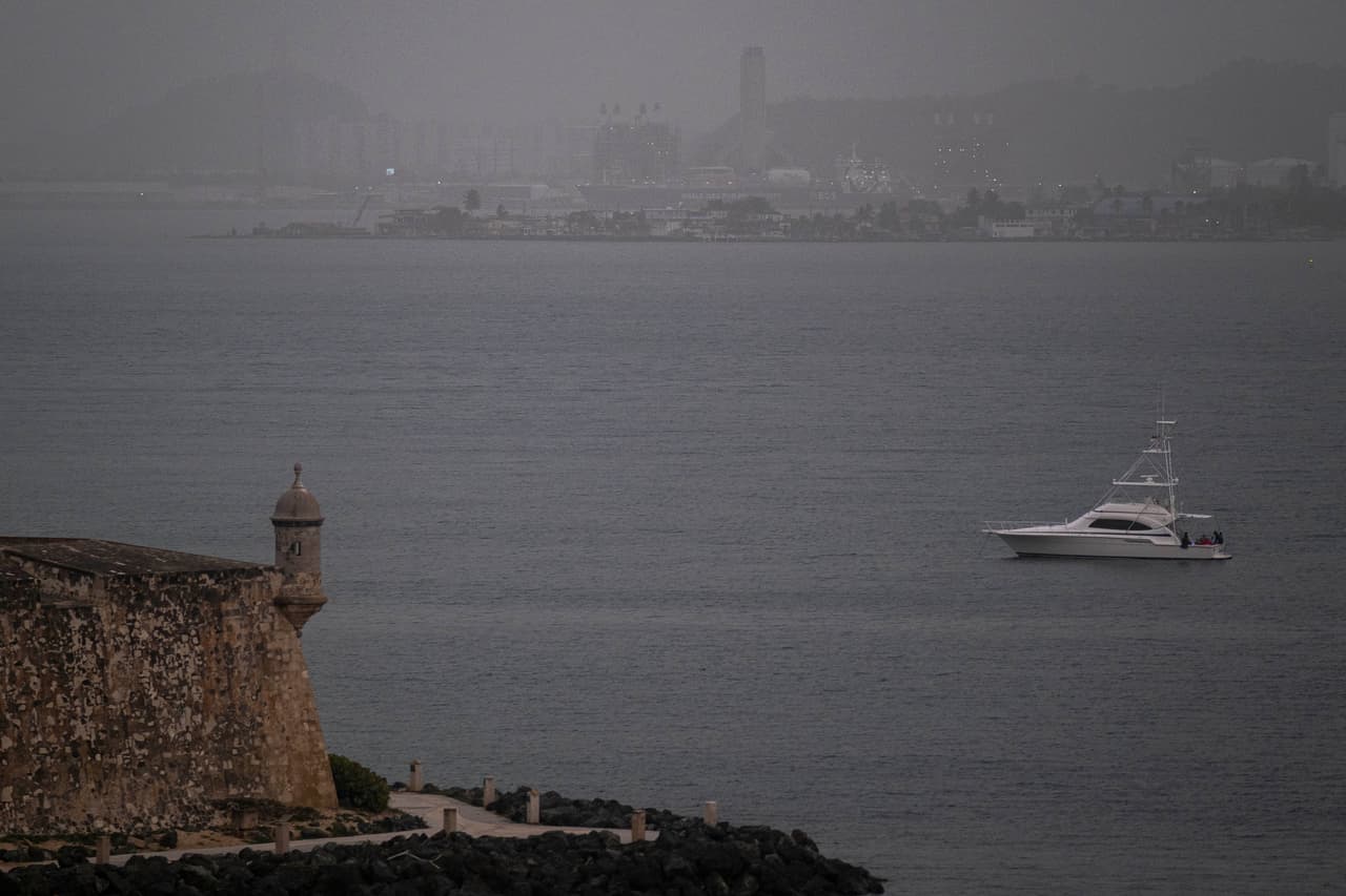 Aunado al fenómeno, las temperaturas alcanzaron una temperatura entre los 37,7 y 41 grados centígrados. se une que las temperaturas alcanzarán entre los entre 37,7 y los 41 grados celsius. Un bote navega por la bahía de San Juan mientras la nube cubre el paisaje.
