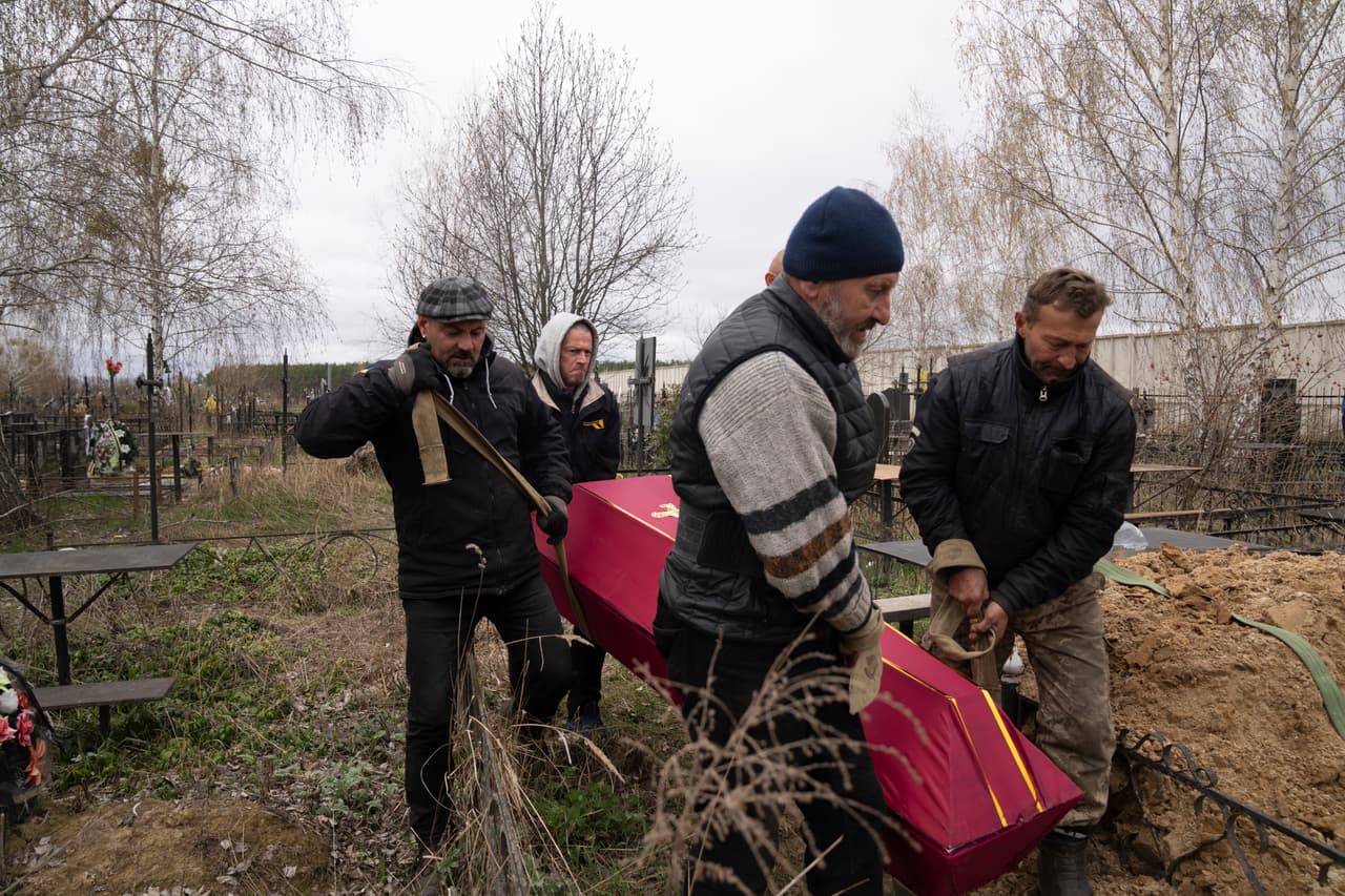 Vlad Minchenko, a la derecha, conduce a un cadáver a su sepultura en Bucha, a las afueras de Kiev, en Ucrania.