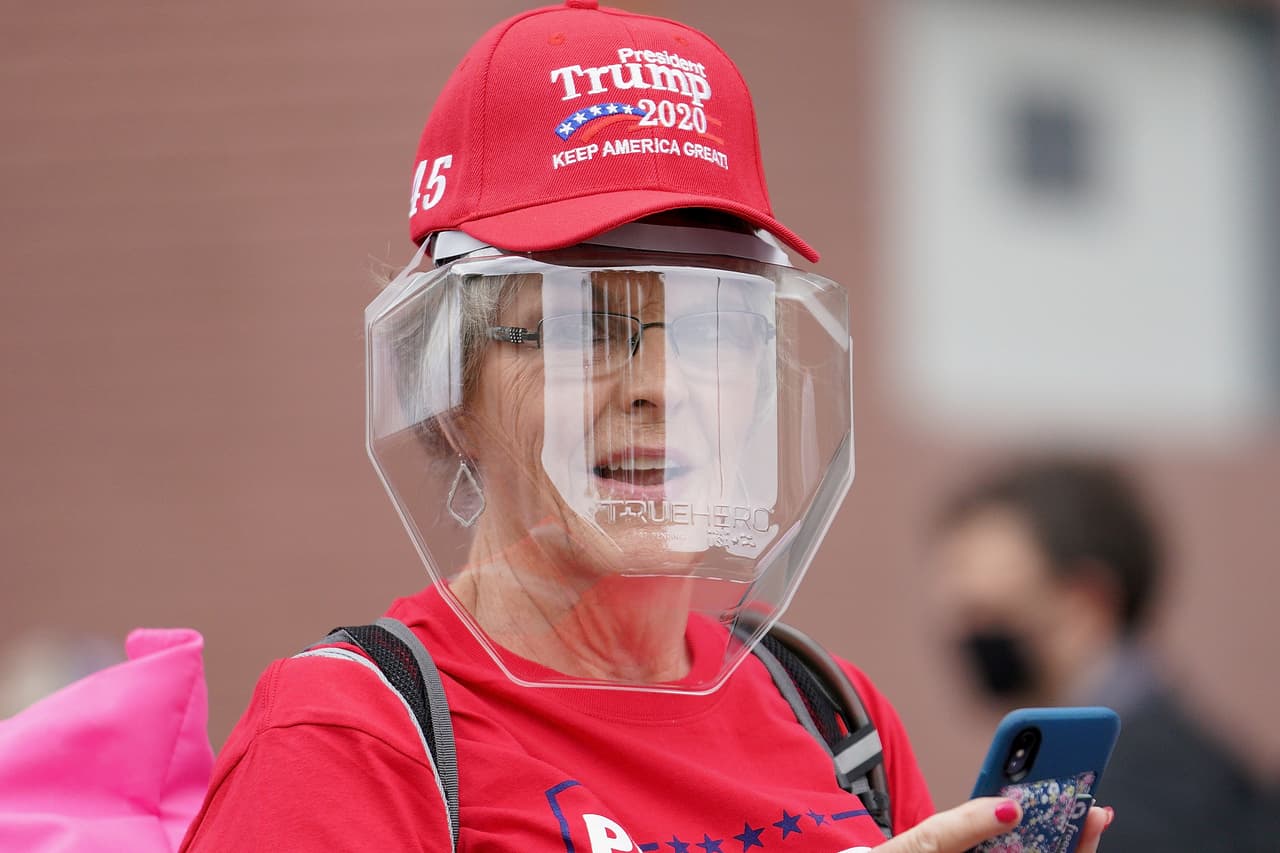 Una partidaria del presidente espera con un escudo facial para evitar contagiarse con el coronavirus. Otros simpatizantes, sin embargo, dijeron al diario 
<i><a href="https://www.washingtonpost.com/nation/2020/06/20/coronavirus-live-updates-us/" target="_blank">The Washington Post </a></i>que tomarán precauciones pero no consideran que el virus sea "una sentencia de muerte". Esto a pesar del aumento sostenido que han reportado casi 20 estados en los últimos días.