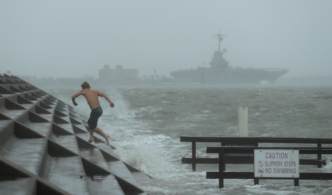 Un hombre salta una de las grandes olas provocadas por Hanna, que también ha traído inundaciones. Los funcionarios locales pidieron el sábado a los residentes que se quedaran en casa.