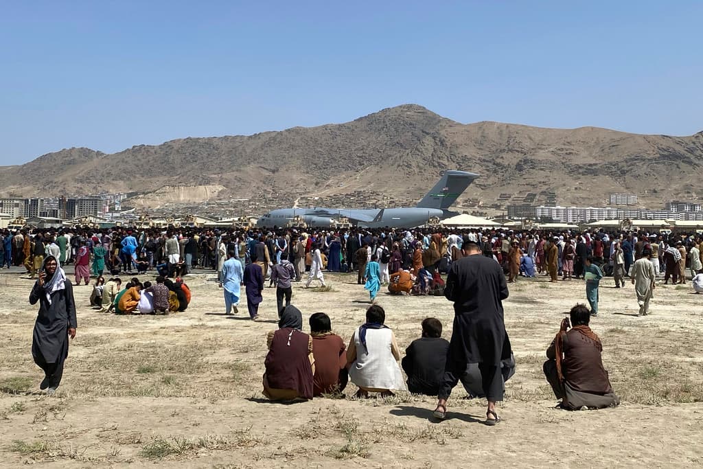 Cientos de personas se reúnen cerca de un avión de transporte C-17 de la Fuerza Aérea de EE. UU. en el perímetro del aeropuerto internacional de Kabul, Afganistán, el 16 de agosto de 2021.