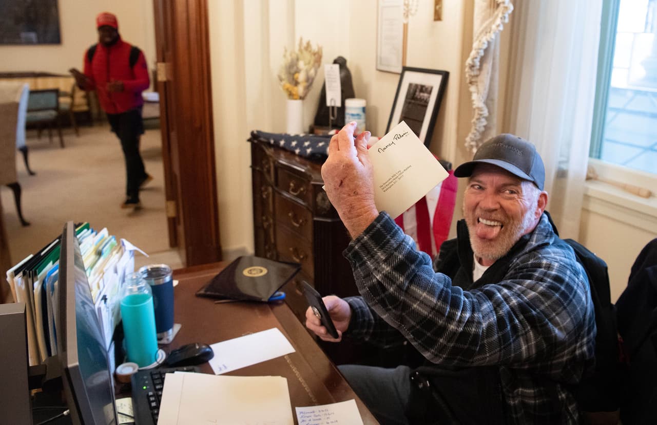 <b>Richard Barnett</b>
<br>
<br>Fue fotografiado manipulando los objetos de la oficina de Nancy Pelosi. Había estado tras las rejas desde enero pero una nueva orden le permitió desde abril esperar la conclusión del juicio en un confinamiento domiciliario condicional que es monitoreado electrónicamente. 
<br>