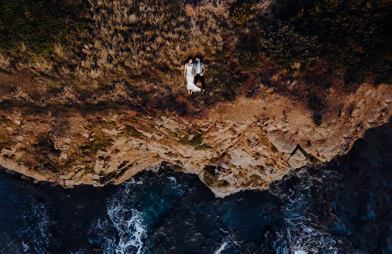 Una pareja descansa en el suelo junto a un impresionante acantilado. La imagen fue finalista en la categoría ‘desde arriba’, que reconoce las tomas aéreas y con drones.