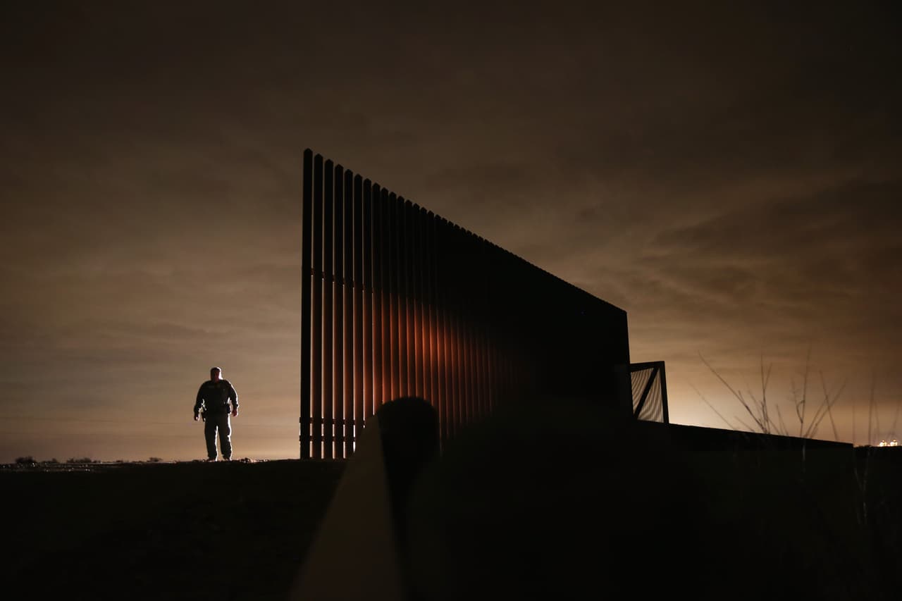 Un agente de la Patrulla Fronteriza de los Estados Unidos se para cerca de una porción de la cerca fronteriza de Estados Unidos y México por La Joya, Texas, durante una patrulla nocturna en el Valle del Río Bravo. 
<br>