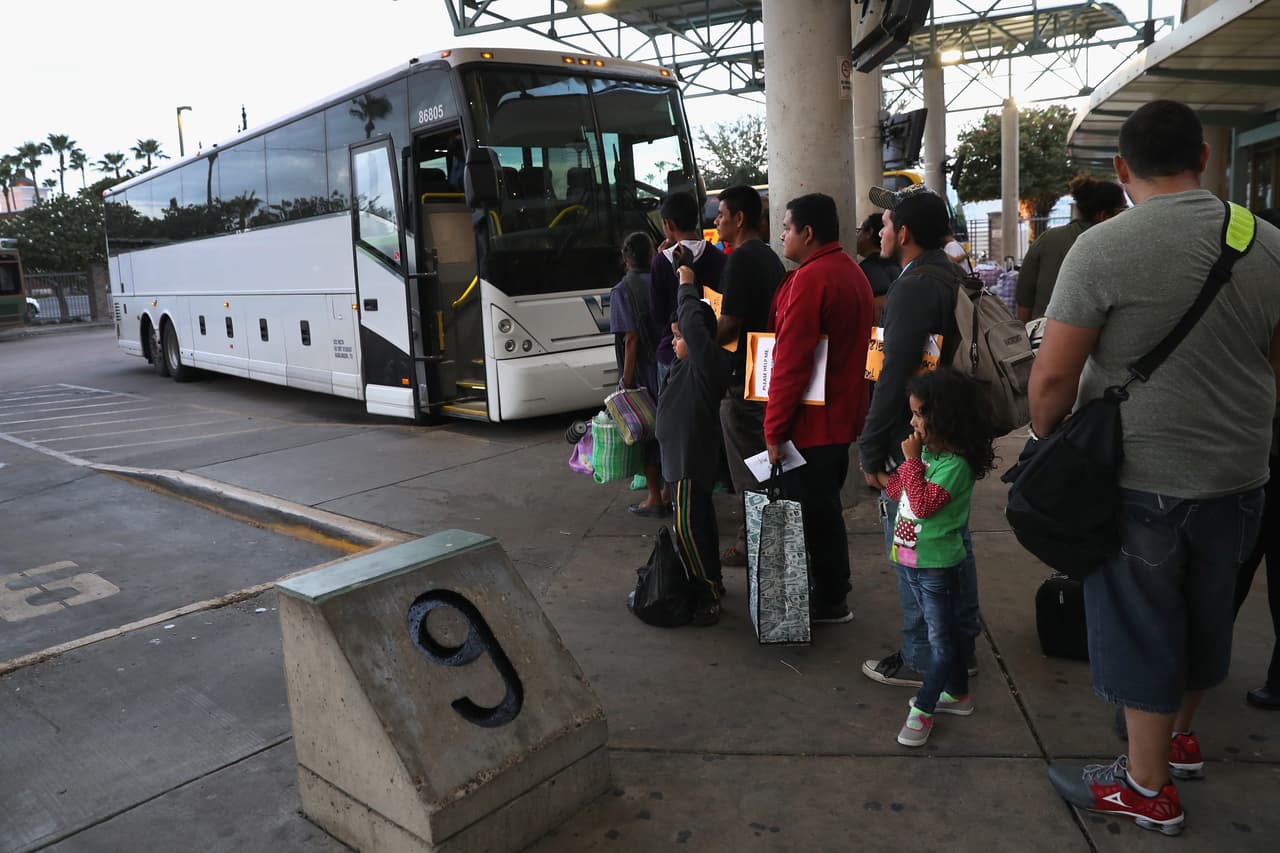 Un grupo de inmigrantes de origen centroamericano forman una fila para tomar un autobús luego de ser procesados por la patrulla fronteriza de McAllen, Texas. Cuando son puestos en libertad se llevan un citatorio para presentarse ante un juez, quien decidirá sus futuros en EEUU.