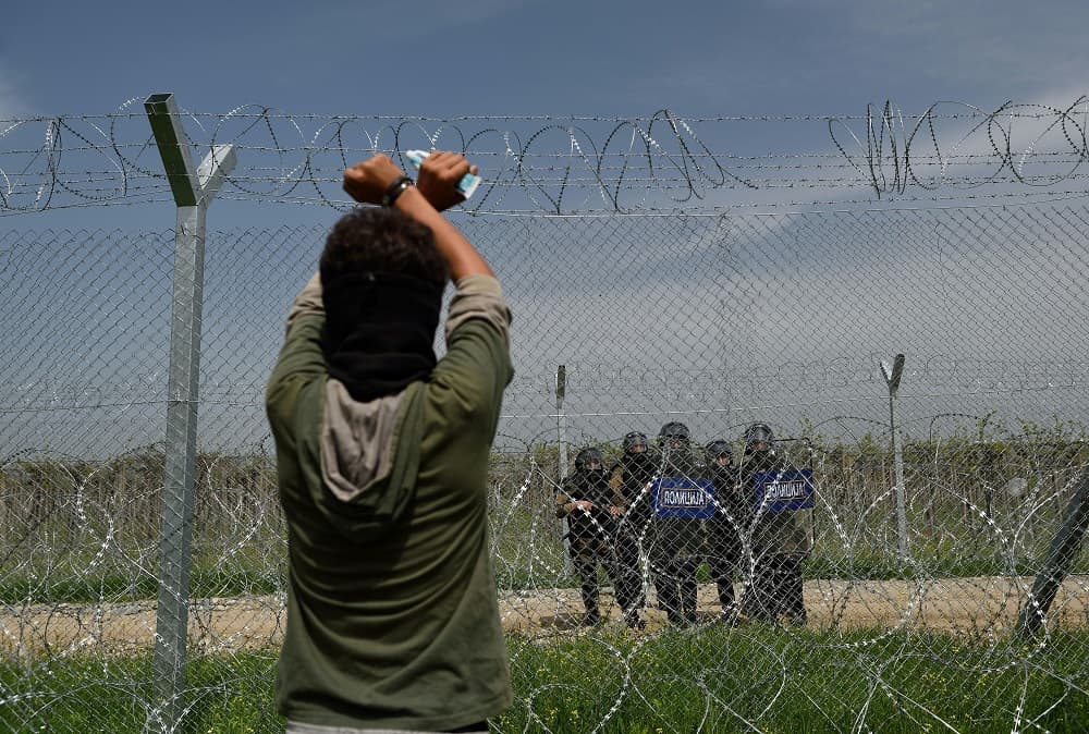 Un joven levanta sus brazos durante una protesta que pide reabrir el paso entre Grecia y Macedonia.