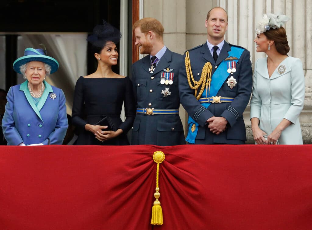 La reina con sus nietos, el príncipe Harry y su esposa, Meghan, y el principe William y su esposa, Kate, duquesa de Cambridge, el 10 de julio de 2018. En 2021 Harry y Meghan se desvincularían de la Casa Real tras denunciar que eran víctimas de acoso y discriminación por parte de los medios de comunicación.
