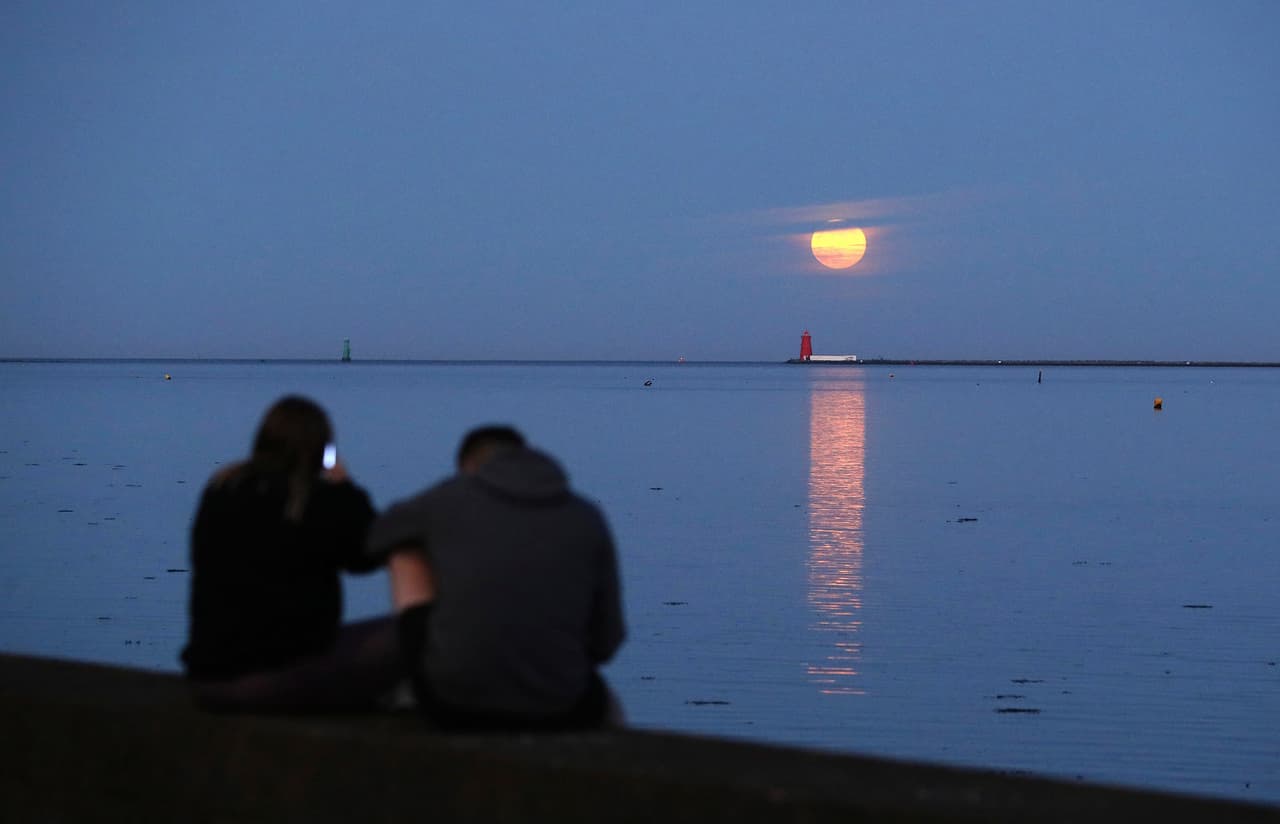 Una pareja contempla la Superluna desde la bahía de Dublín, en Irlanda, este jueves. 
<b>La Superluna es un fenómeno que ocurre cuando la luna está en su punto más cercano a la tierra y se ve más grande de lo habitual.</b>
