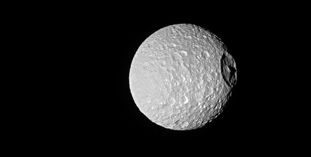 Mimas, igual que la Luna de la Tierra, siempre muestra la misma cara de su superficie a Saturno, es decir, la rotación sobre sí misma está sincronizada con la rotación de Saturno. El cráter Herschel, con su montaña al centro, fue formado por el choque de un meteorito de al menos tres millas de diámetro.