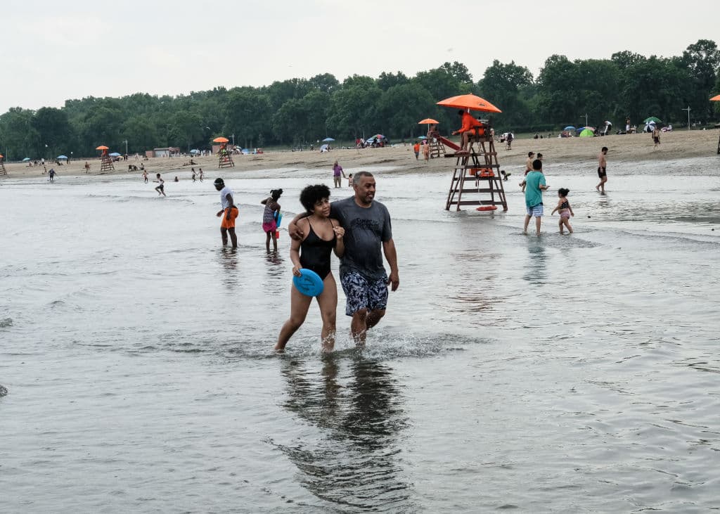 <b><a href="https://www.nycgo.com/venues/orchard-beach">Orchard Beach-Bronx</a></b>
<br>Middletown Road & Stadium Avenue
<br>Tel. (718) 430-1890
<br>
<a href="https://www.google.com/maps/dir/Orchard+Beach,+The+Bronx,+NY/@40.867402,-73.8623333,12z/data=!4m9!4m8!1m0!1m5!1m1!1s0x89c28c5fdfb5d393:0xeb511a8331f79e2f!2m2!1d-73.7922928!2d40.8672934!3e0">Cómo llegar</a> 
<br>Esta playa de 1.1 millas, fue llamada “La Rivera de Nueva York” y fue creada en la década de 1930. Entre las razones por las que se le considera una de las mejores de la ciudad, está el sin fin de actividades que puedes encontrar en la zona de 115 acres que la rodean.
<br>
<br>La playa tiene un paseo de bloques hexagonales, áreas para pícnic, dos parques de juegos para niños y
<b> 26 canchas para deportes como baloncesto y voleibol. </b>
<br>