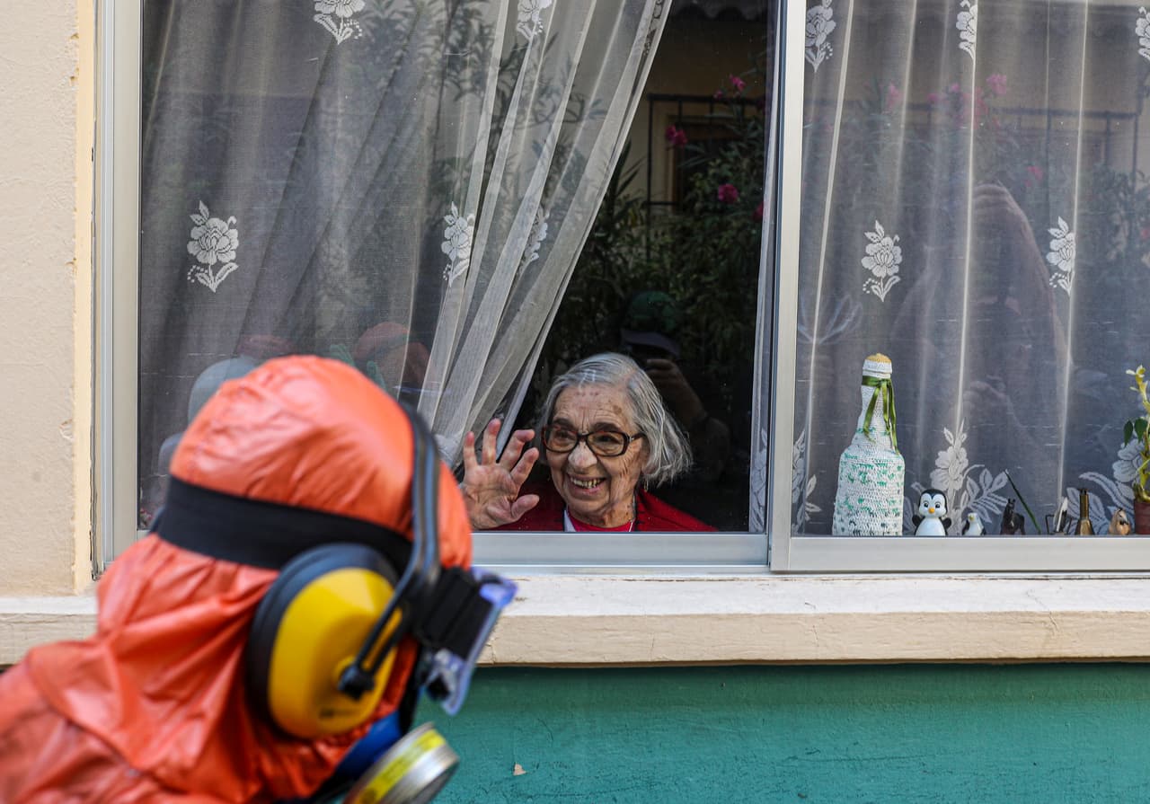 Una mujer en cuarentena saluda para agradecer el trabajo de un empleado de la ciudad durante la desinfección de las calles de Santiago, Chile. 15 de abril.