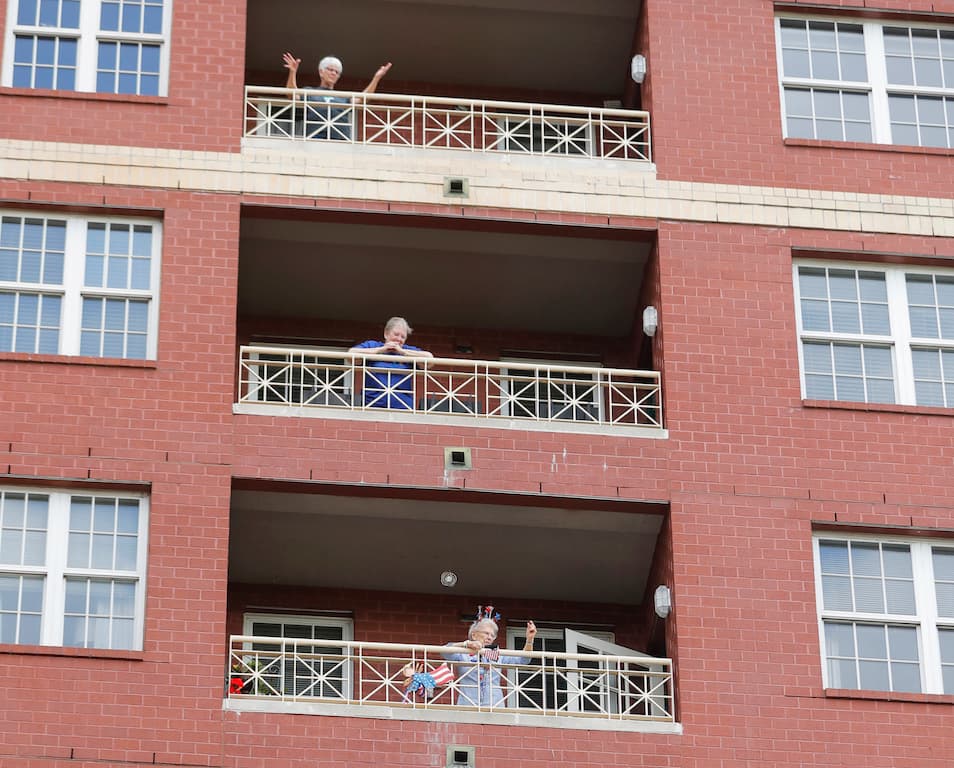 Residentes de retiro Casa Lambeth, en Nueva Orleans, donde ha habido un brote de coronavirus, salen a escuchar música en sus balcones mientras están en cuarentena.