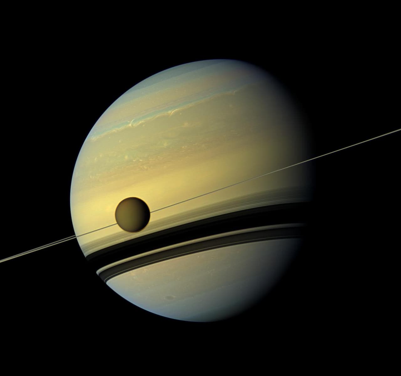 Una luna gigante aparece frente a un planeta gigante en esta visión de color natural de Titán y Saturno. Titán, la luna más grande de Saturno, mide 3,200 millas, o 5,150 kilómetros, y es más grande que el planeta Mercurio.