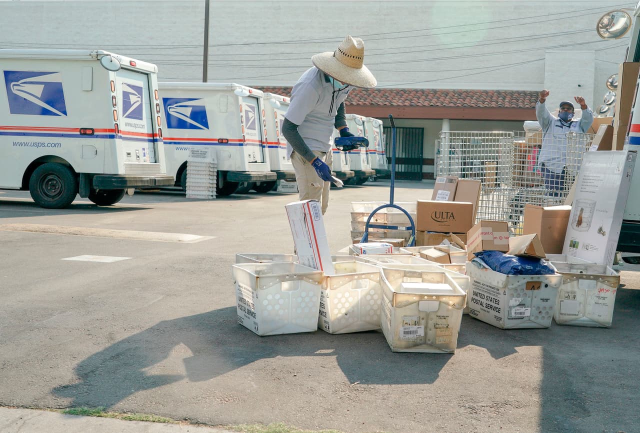 Postal workers sort, load and deliver mails as protesters hold a "Save the Post Office" demonstration outside a United States Postal Service location in Los Angeles, California, on August 22, 2020. - Postmaster General Louis DeJoy on August 21 denied claims he was working to undermine mail delivery, after comments by President Donald Trump raised fears the US Postal Service would be sabotaged to aid his chances in the November elections. (Photo by Kyle Grillot / AFP) (Photo by KYLE GRILLOT/AFP via Getty Images)